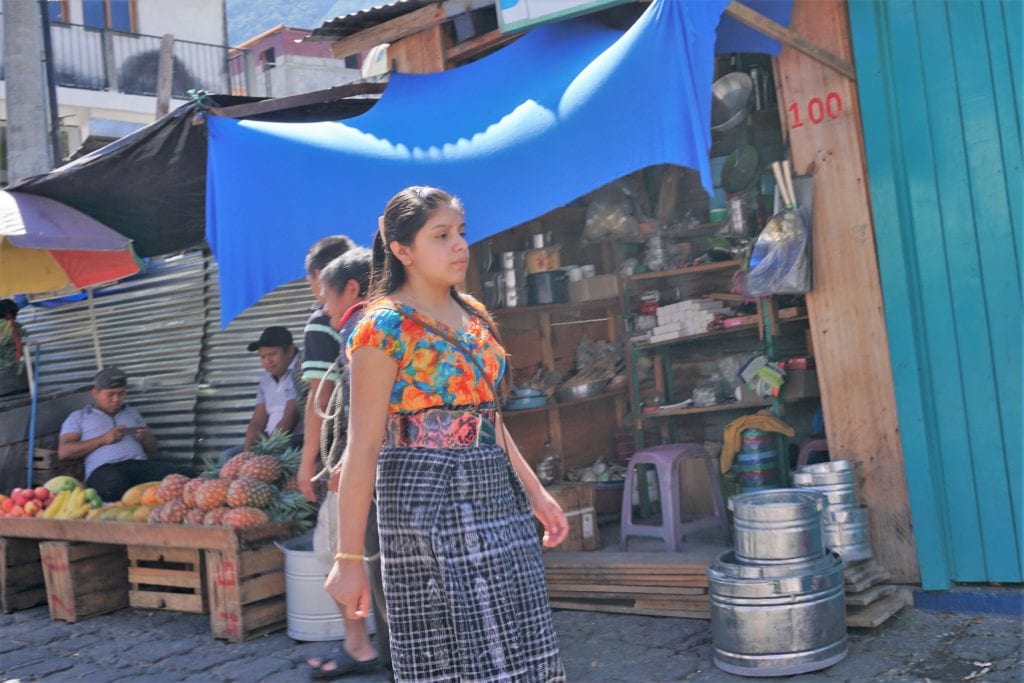 Young lady in Mayan dress walking through local market San Pedro