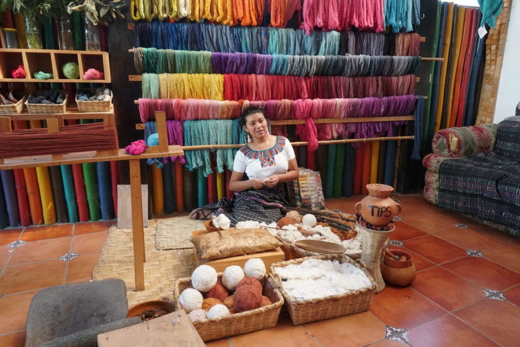 Lady in Mayan dress demonstrating traditional yarn making