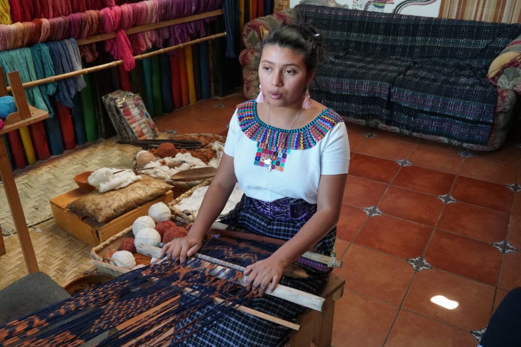 Young lady in Mayan dress demonstrating making fabrics