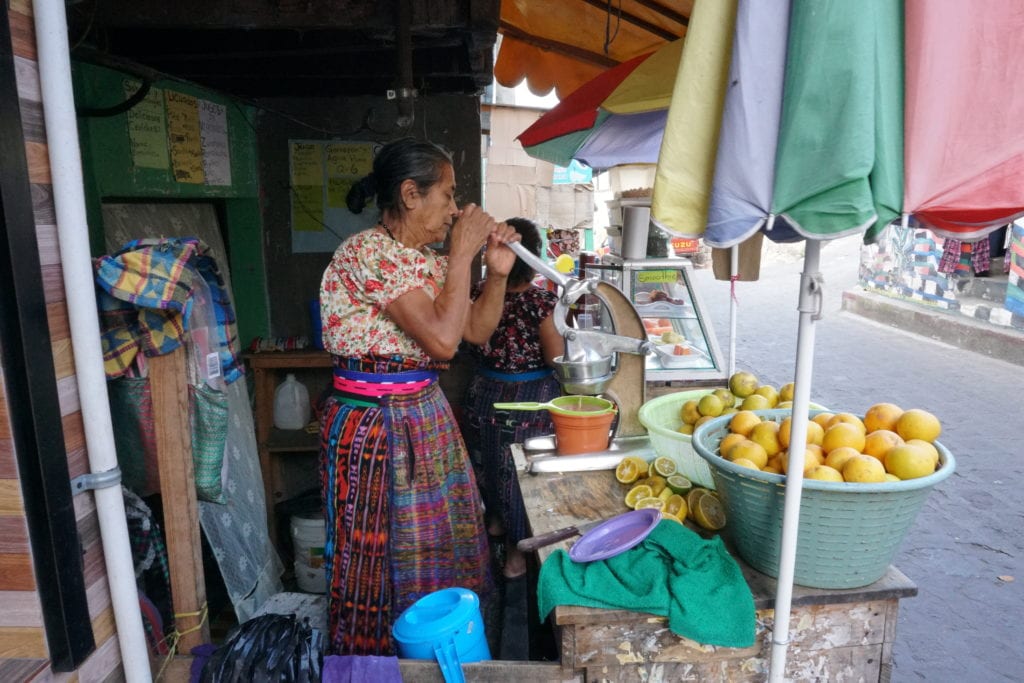 Mayan women squeezing orange juice