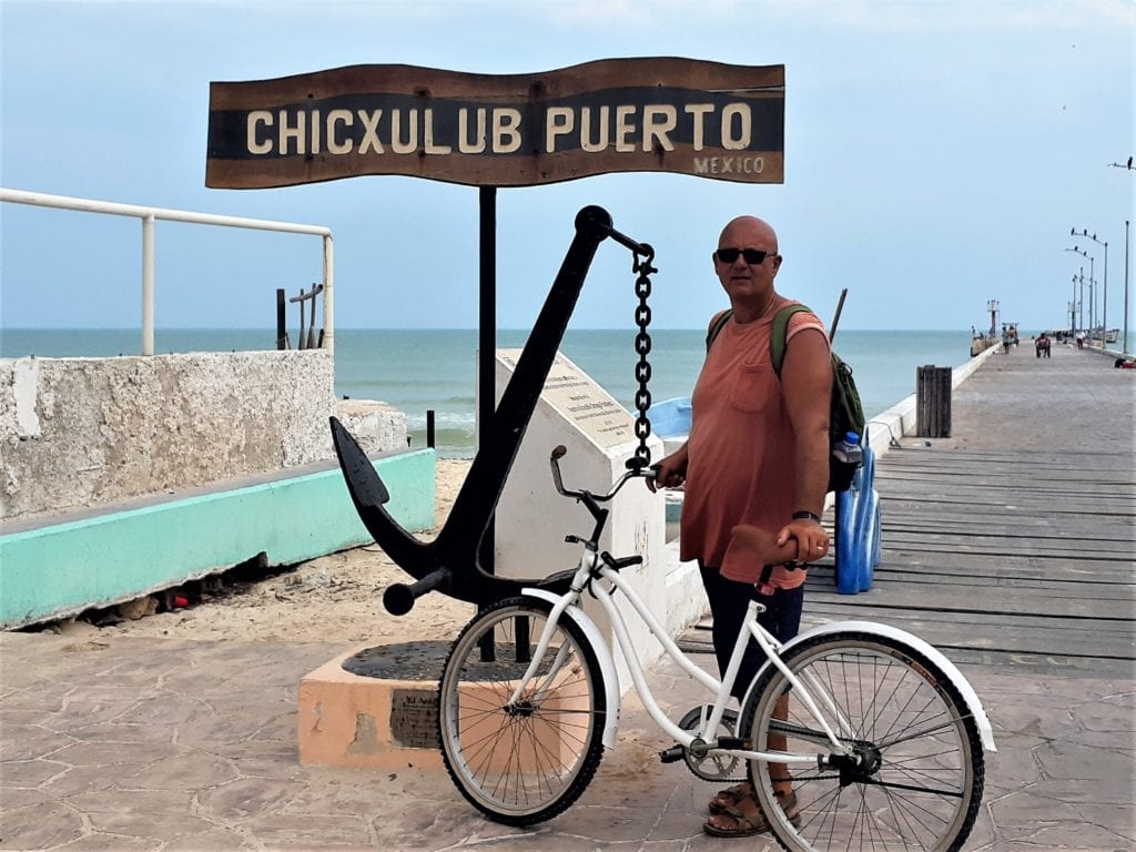 Greg with bike in front of Chicxulub Puerto sign & anchor