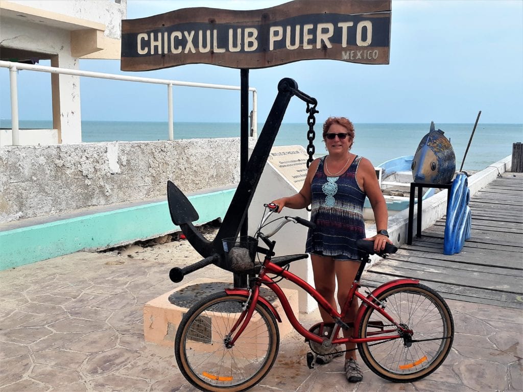 Cindy with bike in front of Chicxulub Puerto sign & anchor