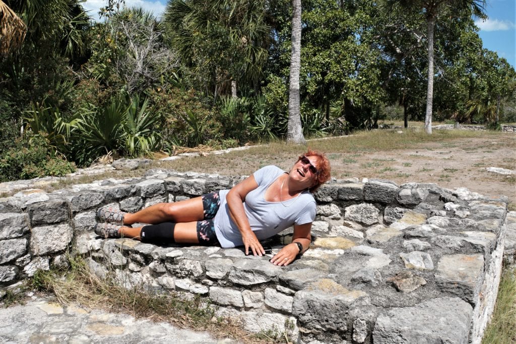 Cindy laying in stone bed at Xcambo Mayan ruin