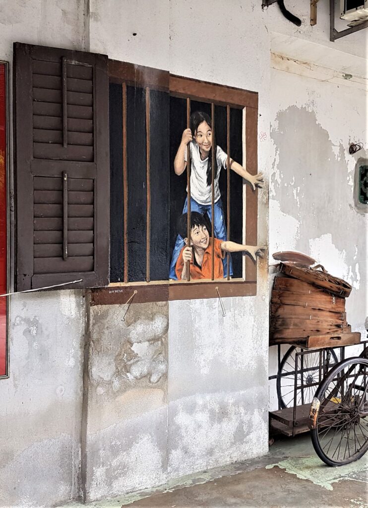 Penang street art shows boy and girl reaching out window for some dim sum in steamer